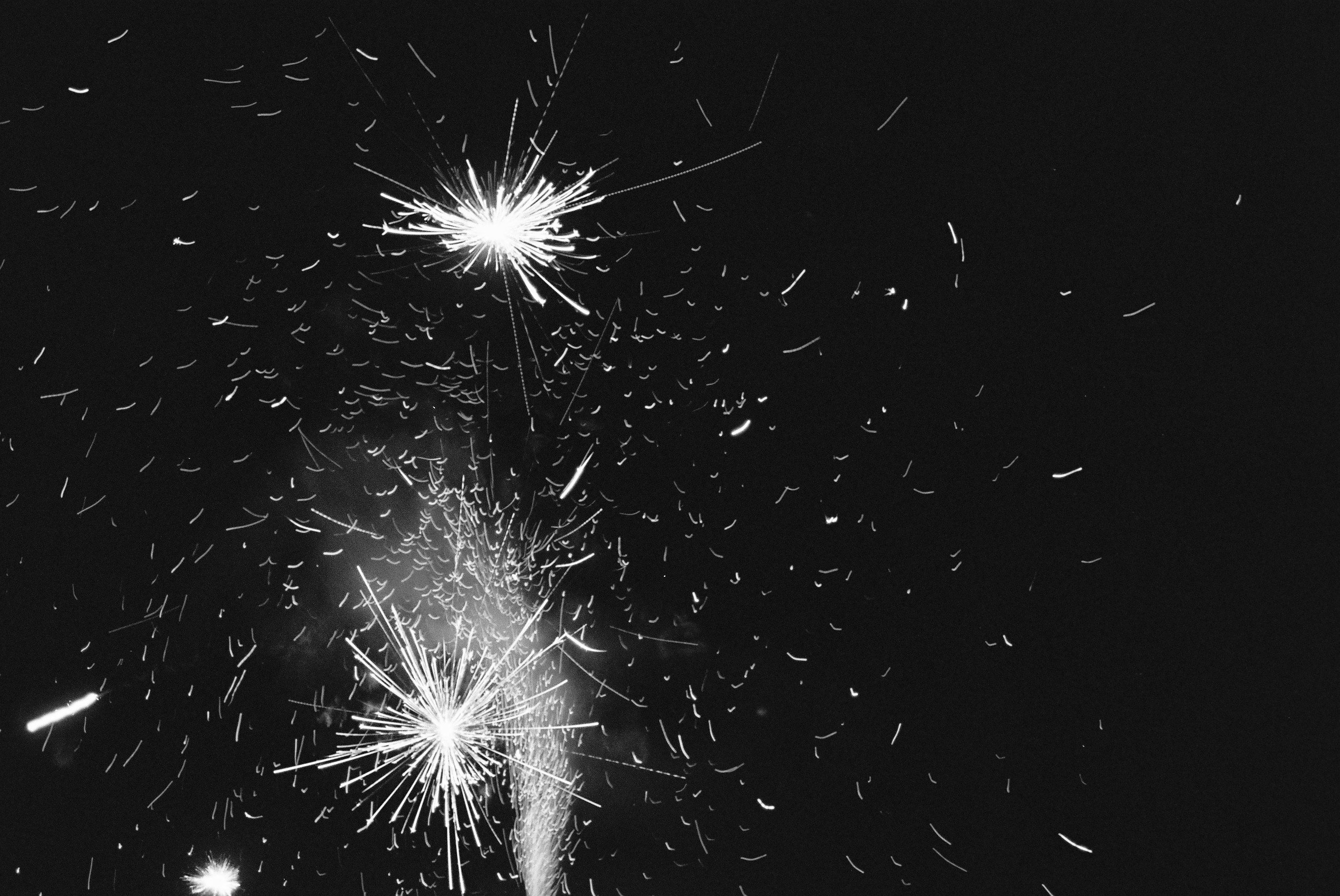 Black and white photo of fireworks against the night sky.